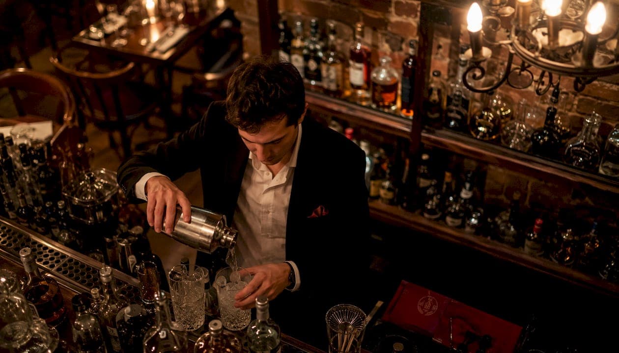 Un barman en pleine préparation de cocktails raffinés lors d’une soirée chic.